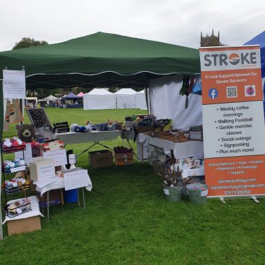 A stall with various items under a green canopy at an outdoor event.