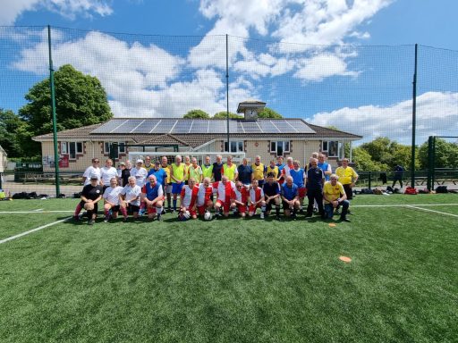 A group of people posing on a football field under a clear blue sky.