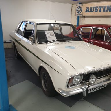 Classic white Austin car parked in a museum display.