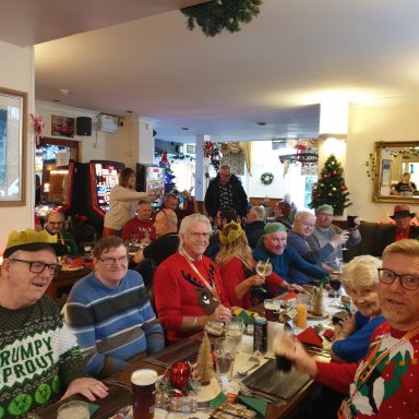 A group of people in festive attire enjoying drinks in a decorated pub.